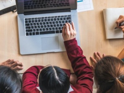 Overhead view of a group of young adults sitting around a table looking at a laptop